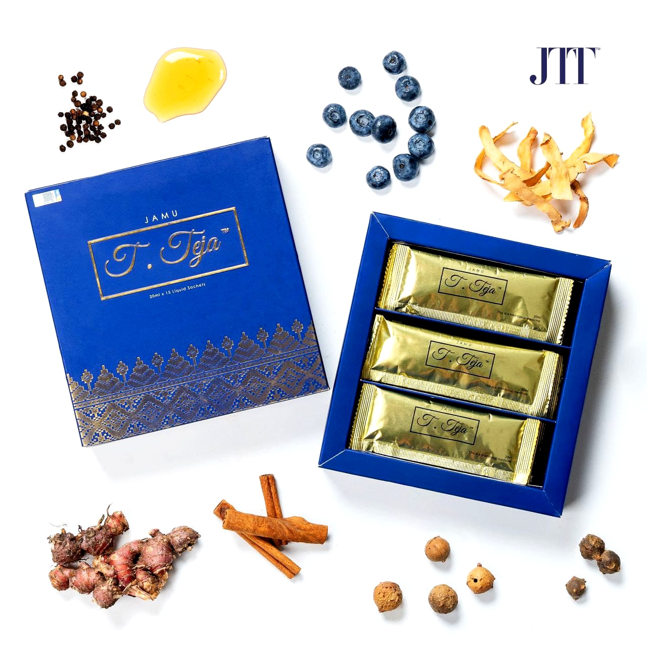 Kotak Jamu Tun Teja terbuka dengan sachet emas, dikelilingi enam ramuan warisan: lada hitam, halia bara, kulit kayu manis, akar serapat, manjakani dan acai berry